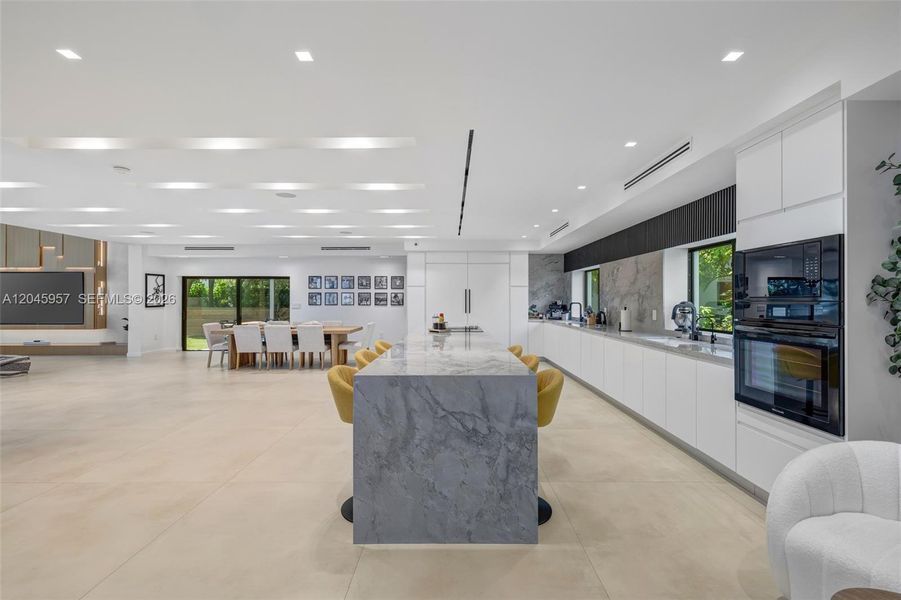Clean lines, natural stone, and custom cabinetry come together to create a timeless kitchen that serves as the centerpiece of the home.