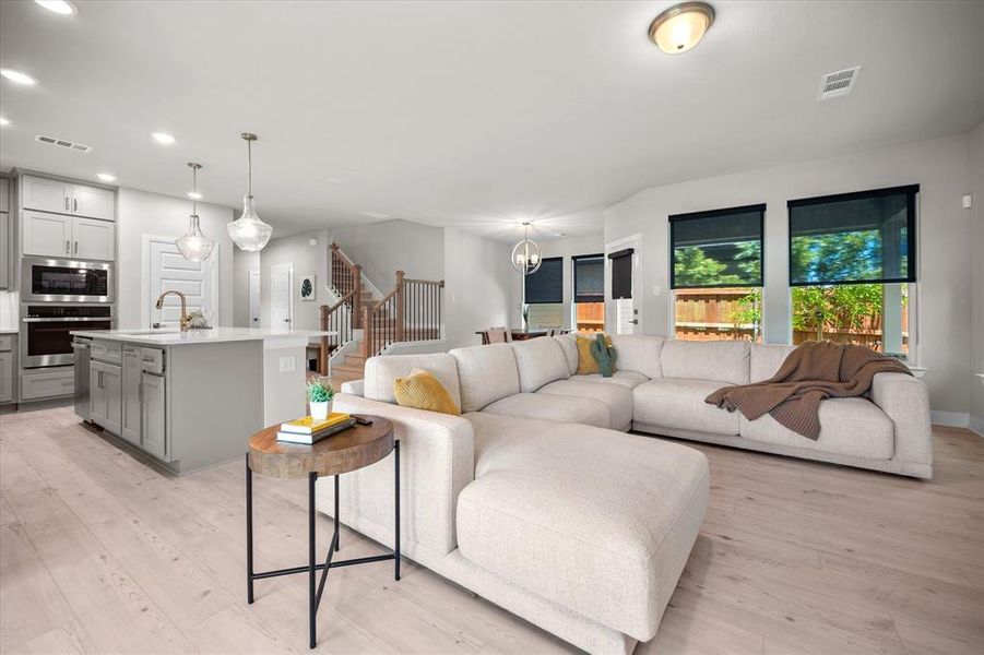 Living area featuring stairs, light wood-style floors, and recessed lighting Living area featuring stairs, light wood-style floors, and recessed lighting