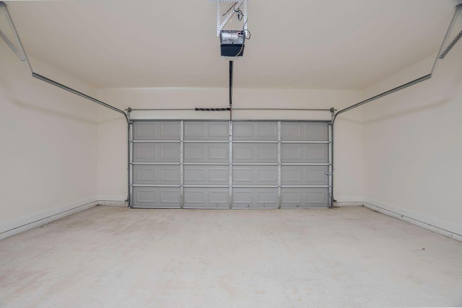 Garage featuring a garage door opener and baseboards Garage featuring a garage door opener and baseboards