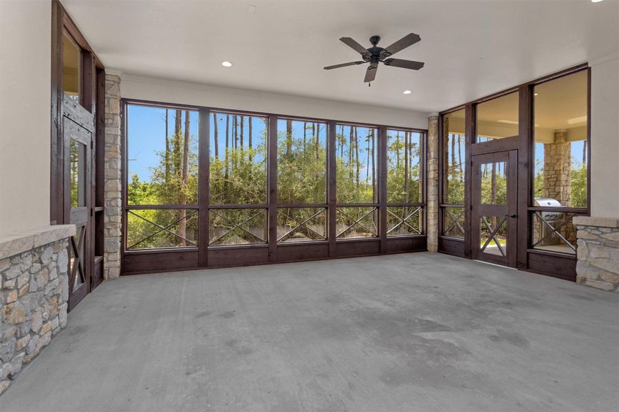This expansive screened-in patio offers a tranquil retreat surrounded by wooded views, complete with a ceiling fan and direct access to the outdoor kitchen and covered patio.