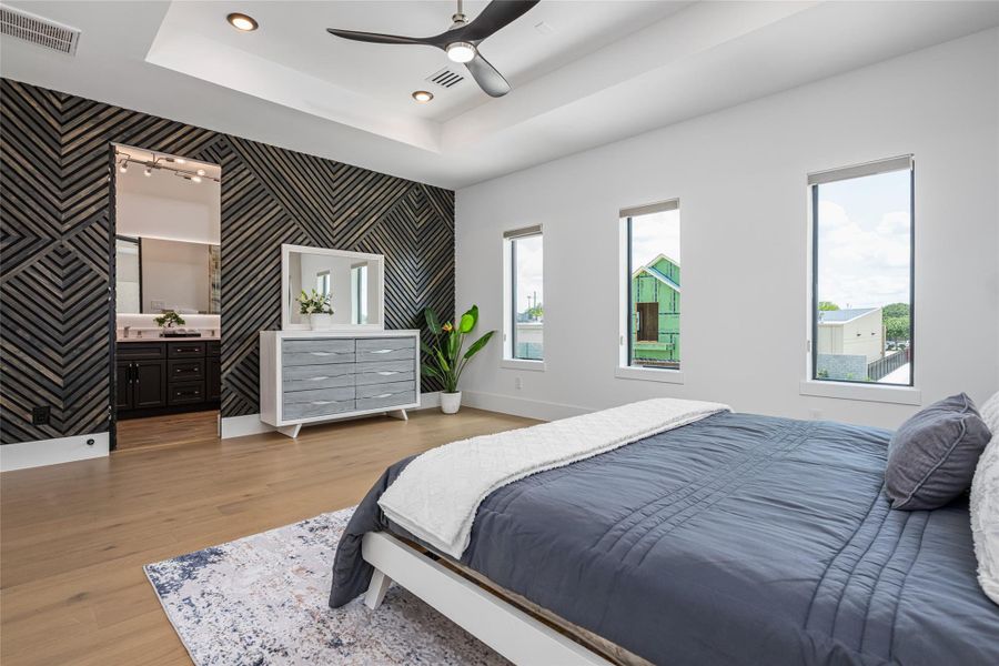 The primary bedroom is a sunlit sanctuary, complete with elegant wood floors, tray ceiling, and a thoughtfully designed custom closet The primary bedroom is a sunlit sanctuary, complete with elegant wood floors, tray ceiling, and a thoughtfully designed custom closet