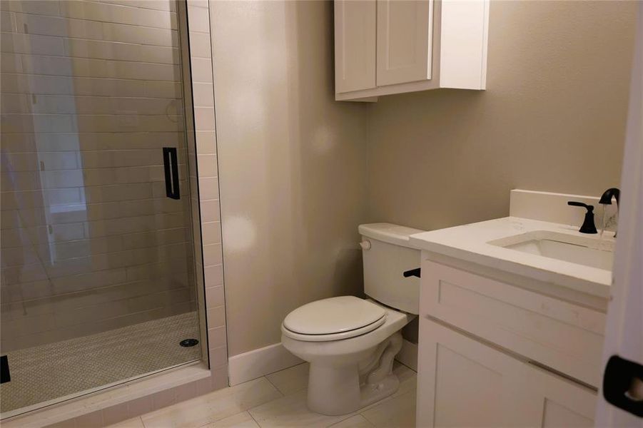 Bathroom with tile patterned floors, vanity, an enclosed shower, and toilet