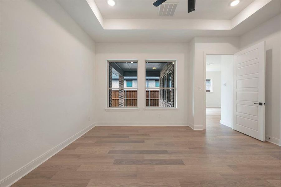 This room features light-colored hardwood flooring, white walls, and a tray ceiling with recessed lighting