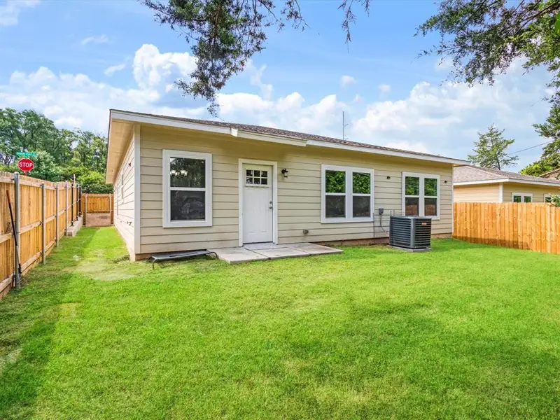 Expansive fenced backyard featuring a substantial lawn area, a concrete patio, and a light-colored siding exterior with multiple windows