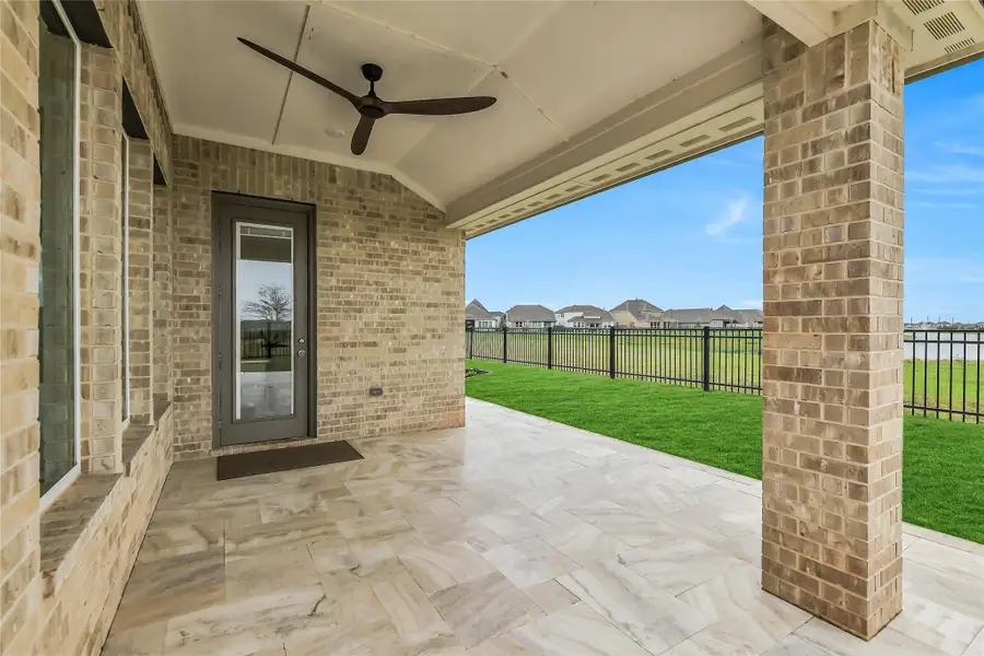 Inviting covered patio with ceiling fan and brick columns, creating a comfortable outdoor retreat designed for year-round enjoyment.