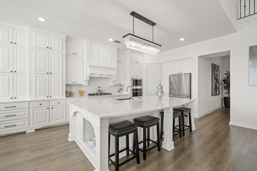 The kitchen features a 10-foot by 6-foot island with Quartz counters, an eat-up breakfast bar and a deep composite sink with a satin nickel faucet. A decorative chandelier illuminates the island, while storage on both ends of the island adds functionality.