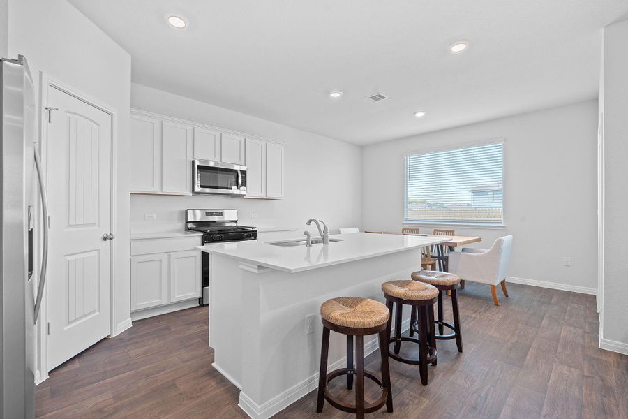 Kitchen with appliances with stainless steel finishes, white cabinetry, dark wood finished floors, a kitchen island with sink, and recessed lighting Kitchen with appliances with stainless steel finishes, white cabinetry, dark wood finished floors, a kitchen island with sink, and recessed lighting