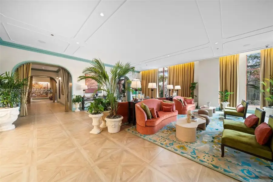 Expansive room featuring intricate parquet wood flooring, decorative ceiling molding, arched entries with accent trim, and floor-to-ceiling windows