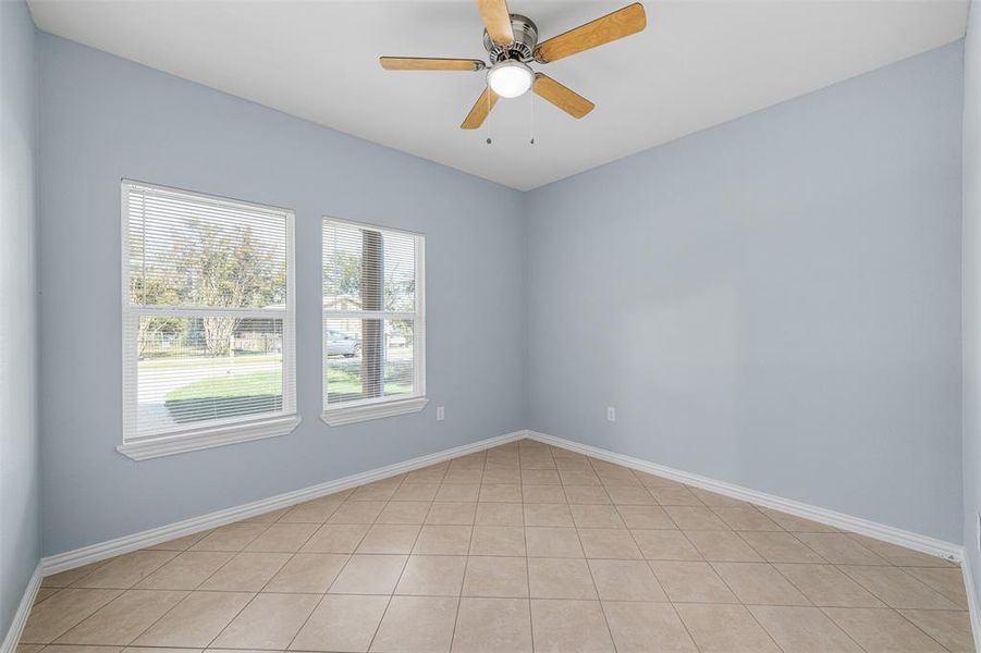 Tiled spare room featuring ceiling fan