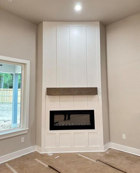 Electric Fireplace with a Modern White Surround Accent Wall and a Wooden Beam Mantel *Paper covering the Floor*