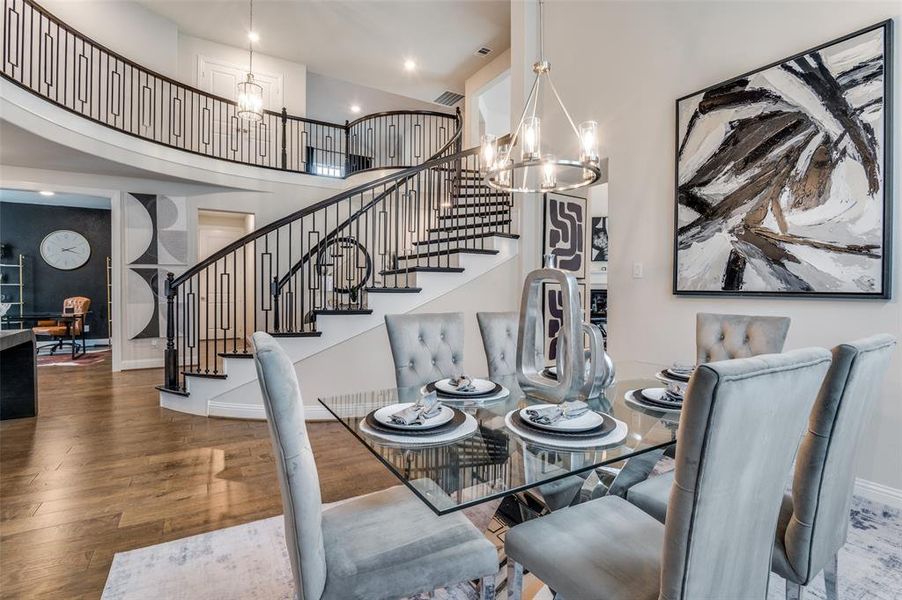 Dining area with a chandelier, wood finished floors, a towering ceiling, stairs, and recessed lighting