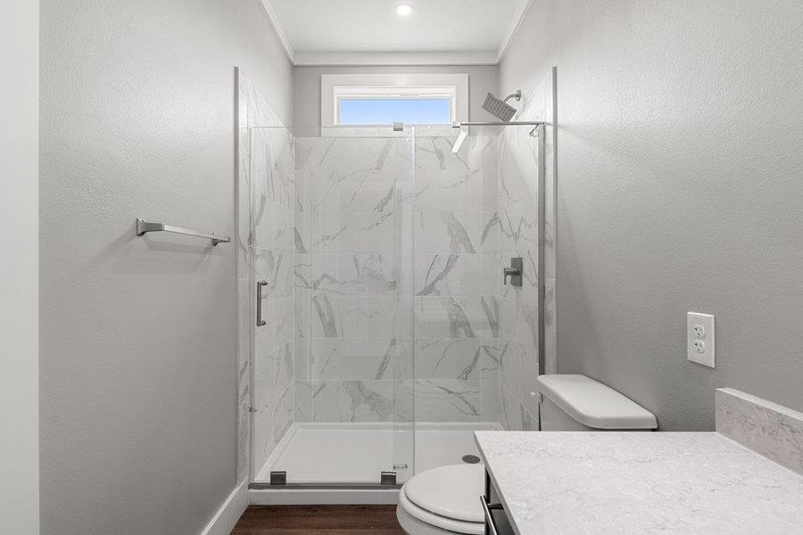 Bathroom with vanity, a marble finish shower, dark wood-style flooring, and a textured wall
