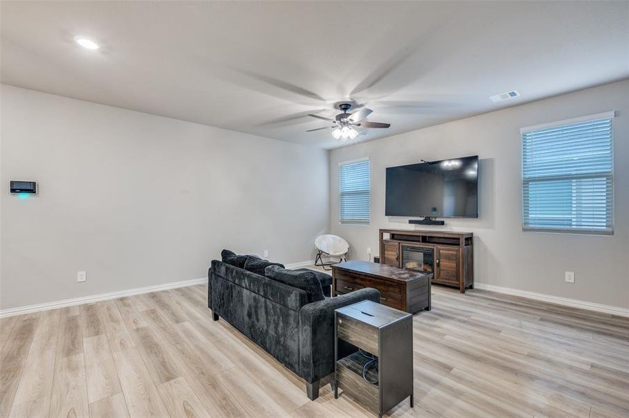 Living area with light wood-type flooring and a ceiling fan