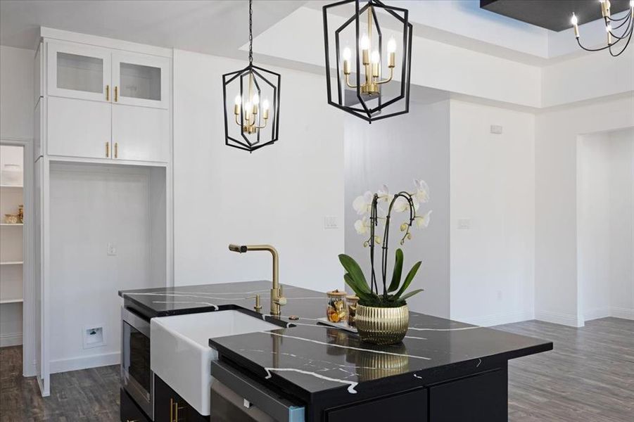 Kitchen featuring glass insert cabinets, a kitchen island, white cabinets, dark cabinetry, and decorative light fixtures