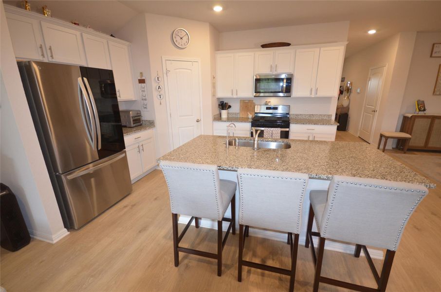 Kitchen with appliances with stainless steel finishes, a kitchen breakfast bar, white cabinets, recessed lighting, and a center island with sink Kitchen with appliances with stainless steel finishes, a kitchen breakfast bar, white cabinets, recessed lighting, and a center island with sink