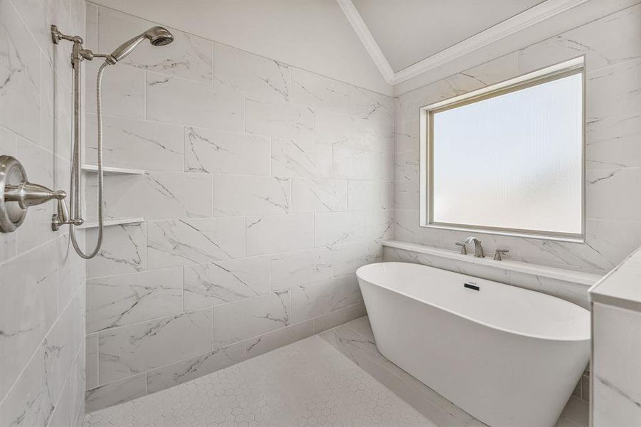 Full bath featuring a freestanding tub, ornamental molding, a marble finish shower, lofted ceiling, and tile walls