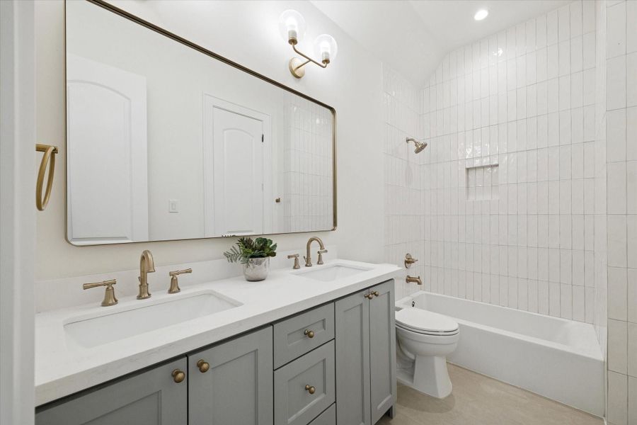 Guest bath with quartz vanity, stylish tile, modern fixtures, and a shower / tub combination.
