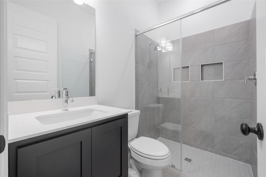 Bathroom featuring a tile shower and vanity
