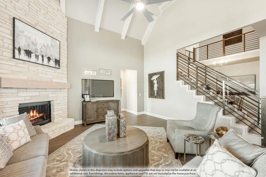 Living room with vaulted ceiling, stone fireplace, and open staircase with metal railing