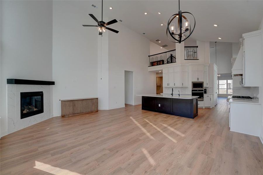 Kitchen featuring a tile fireplace, oven, open floor plan, light countertops, and stainless steel microwave