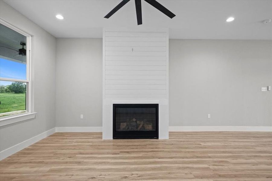Unfurnished living room with a ceiling fan, a fireplace, light wood-style flooring, and recessed lighting