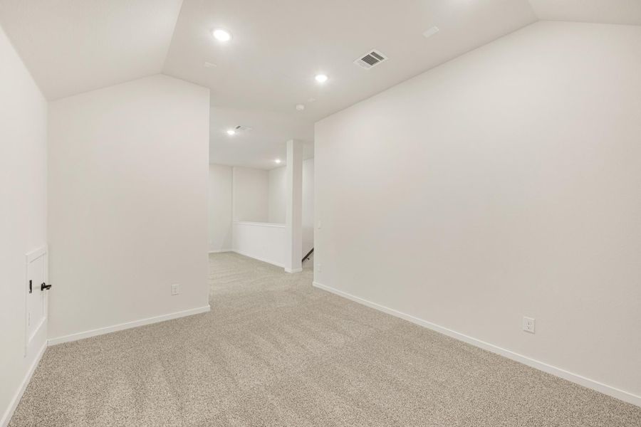 Empty finished basement with white walls, beige carpet, recessed lighting, and a staircase opening