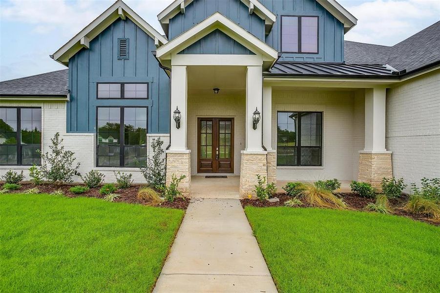 View of exterior entry with french doors and a lawn