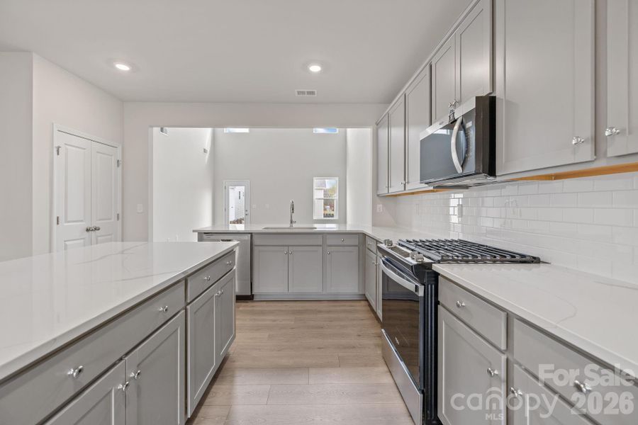 The kitchen features quartz countertops, gas range and gray cabinetry The kitchen features quartz countertops, gas range and gray cabinetry