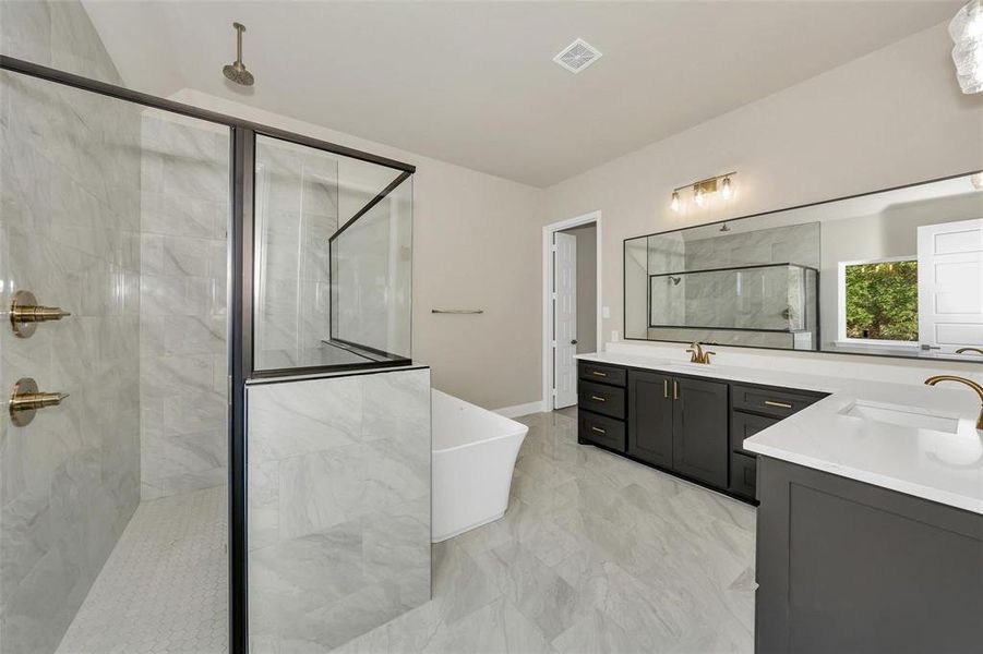 Bathroom with a stall shower, two vanities, a soaking tub, and light marble finish flooring