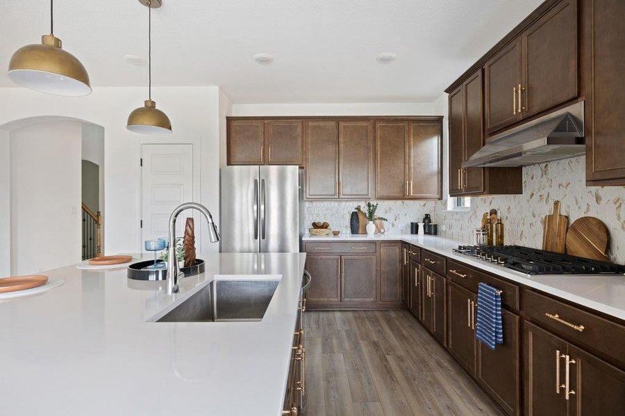 Kitchen featuring decorative light fixtures, dark wood-style flooring, stainless steel appliances, dark wood finish cabinetry, and decorative backsplash Kitchen featuring decorative light fixtures, dark wood-style flooring, stainless steel appliances, dark wood finish cabinetry, and decorative backsplash