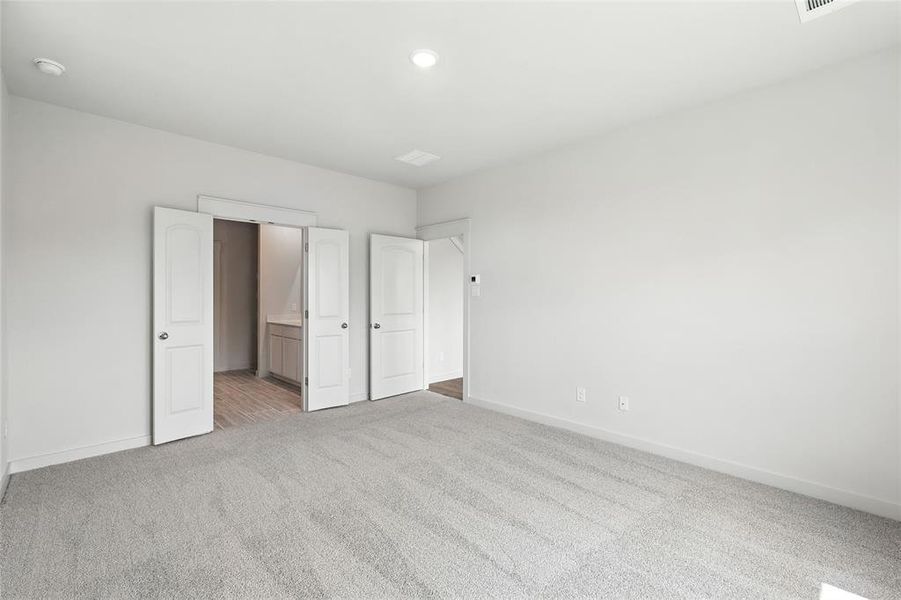 Unfurnished bedroom with light colored carpet, connected bathroom, and recessed lighting Unfurnished bedroom with light colored carpet, connected bathroom, and recessed lighting