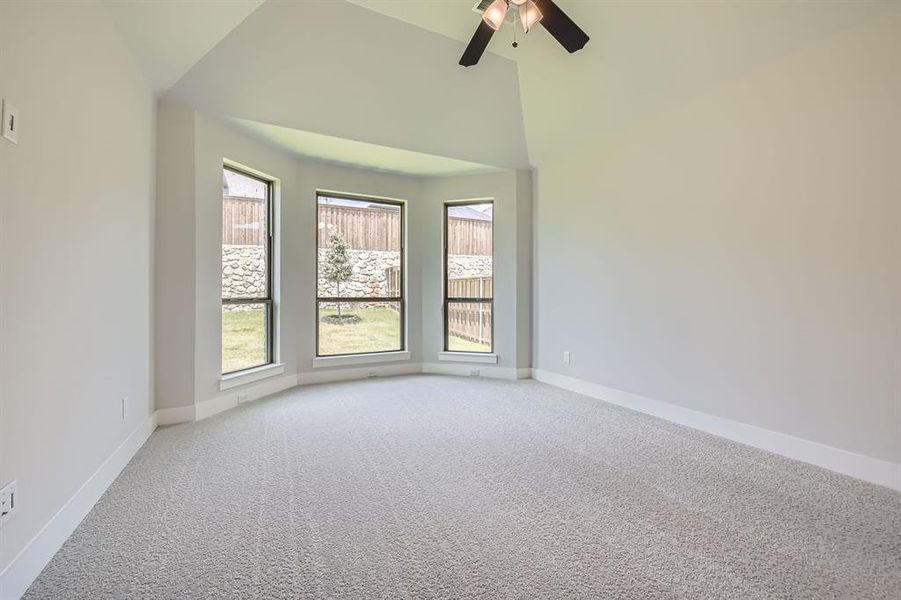Carpeted spare room featuring ceiling fan and high vaulted ceiling Carpeted spare room featuring ceiling fan and high vaulted ceiling