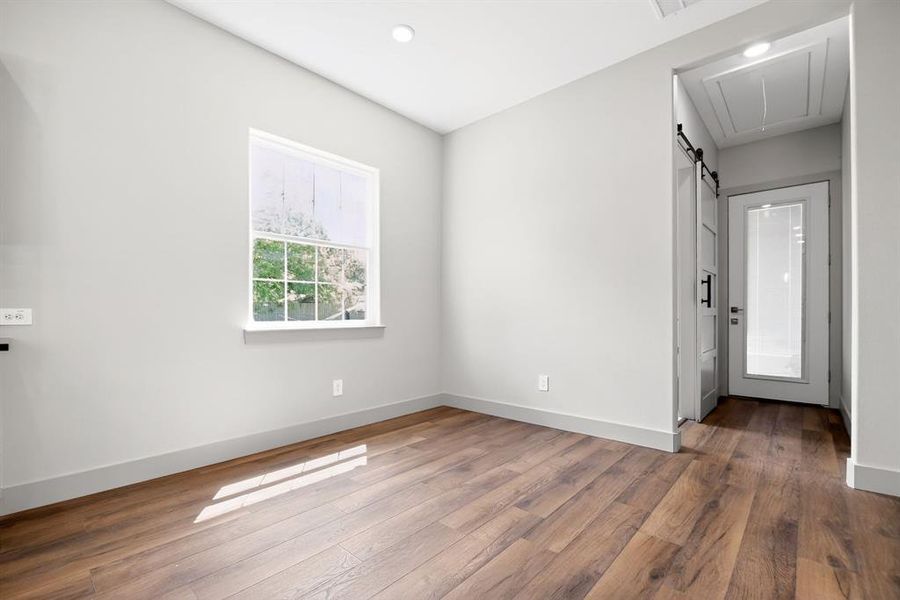 Unfurnished room with hardwood / wood-style flooring, a barn door, and recessed lighting Unfurnished room with hardwood / wood-style flooring, a barn door, and recessed lighting