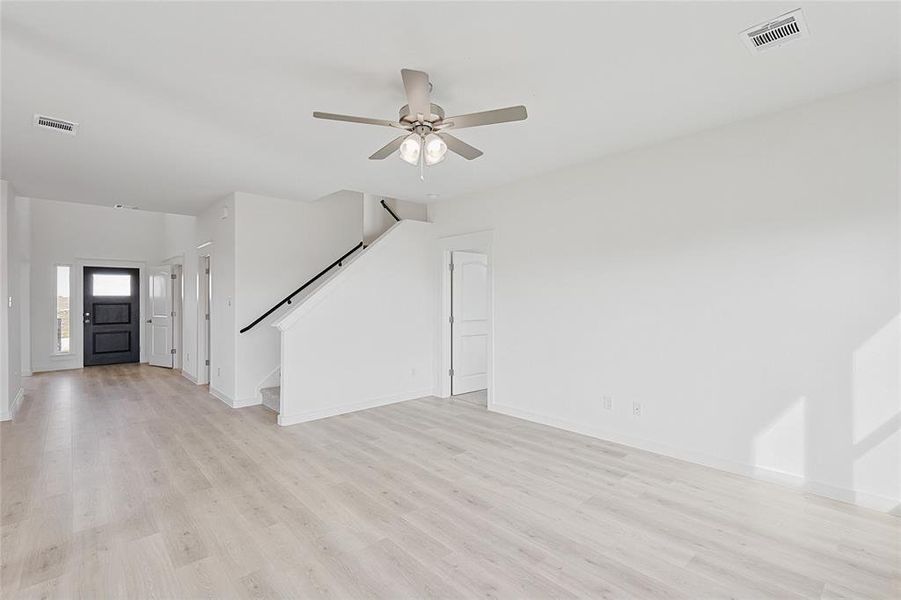 Unfurnished living room featuring light wood-type flooring and ceiling fan