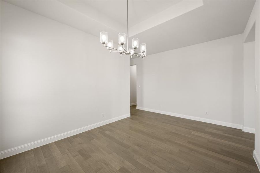 Empty room featuring a chandelier, dark wood-type flooring, and baseboards Empty room featuring a chandelier, dark wood-type flooring, and baseboards
