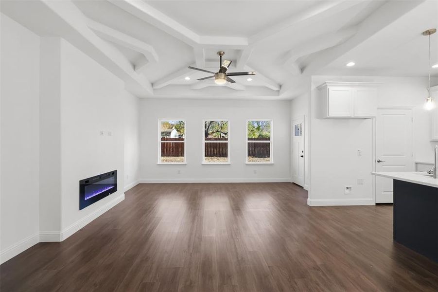 Unfurnished living room featuring ceiling fan, beam ceiling, and dark wood-type flooring