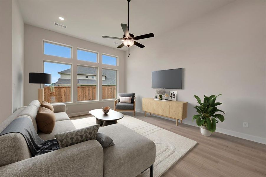 Living area with a ceiling fan, light wood finished floors, recessed lighting, and a high ceiling