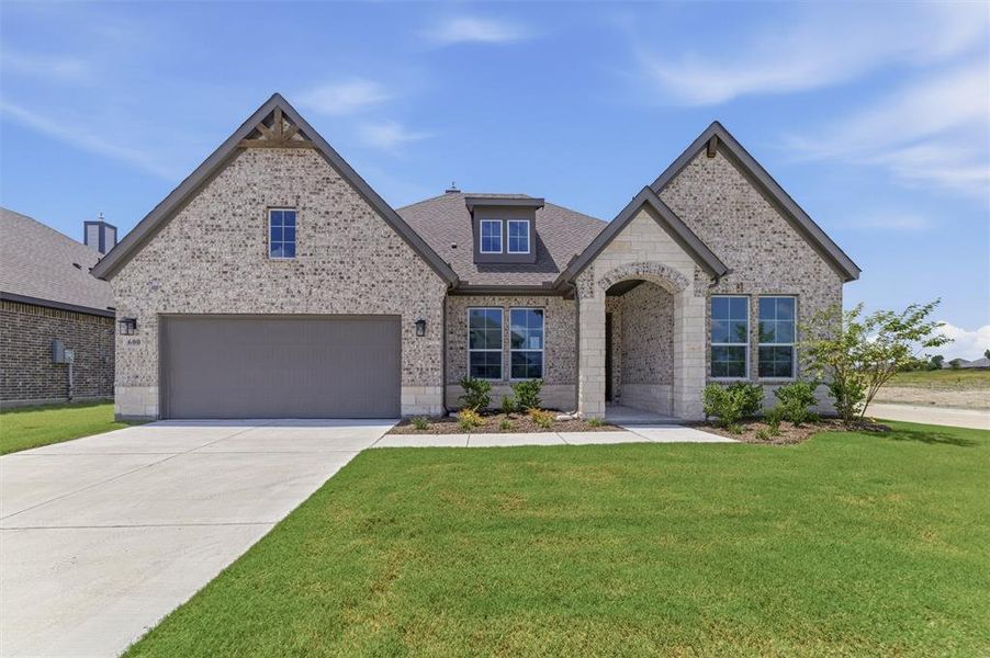Brick facade residence featuring a two-car garage, an arched stone entry, a dormer window, and gabled rooflines Brick facade residence featuring a two-car garage, an arched stone entry, a dormer window, and gabled rooflines