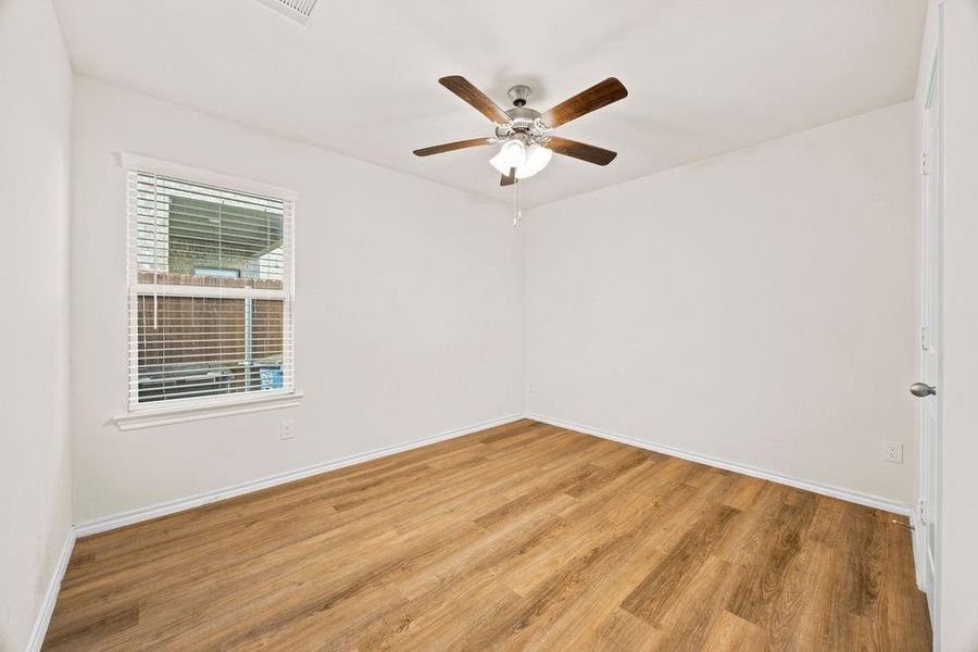 Bright room featuring wood-finish flooring and a ceiling fan with integrated lighting Bright room featuring wood-finish flooring and a ceiling fan with integrated lighting