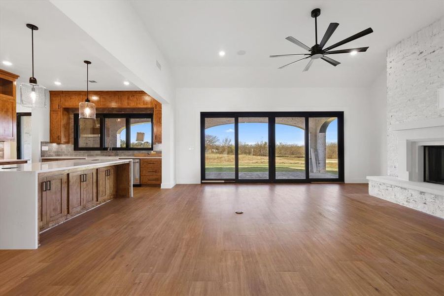 Unfurnished living room featuring dark wood finished floors, healthy amount of natural light, a fireplace, and ceiling fan