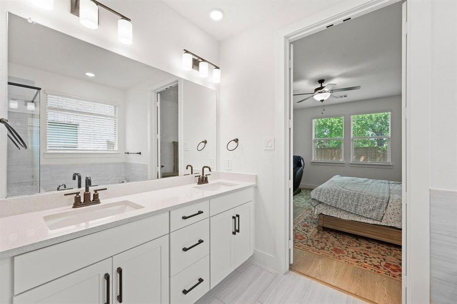 Dual vanity with white cabinetry, quartz-finish countertops, and bronze-finish fixtures Dual vanity with white cabinetry, quartz-finish countertops, and bronze-finish fixtures