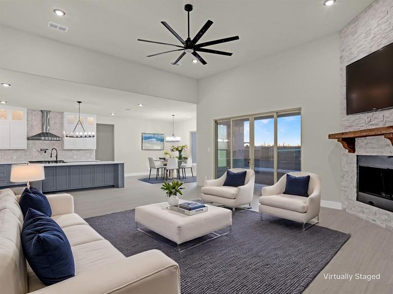 Living room with sink, a stone fireplace, a chandelier, and light hardwood / wood-style floors