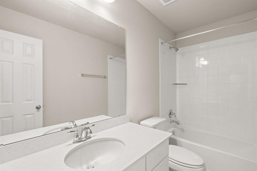 The secondary bath features tile flooring, white cabinetry and light countertops and a shower/tub combo. Perfect for accommodating any visiting family and friends.