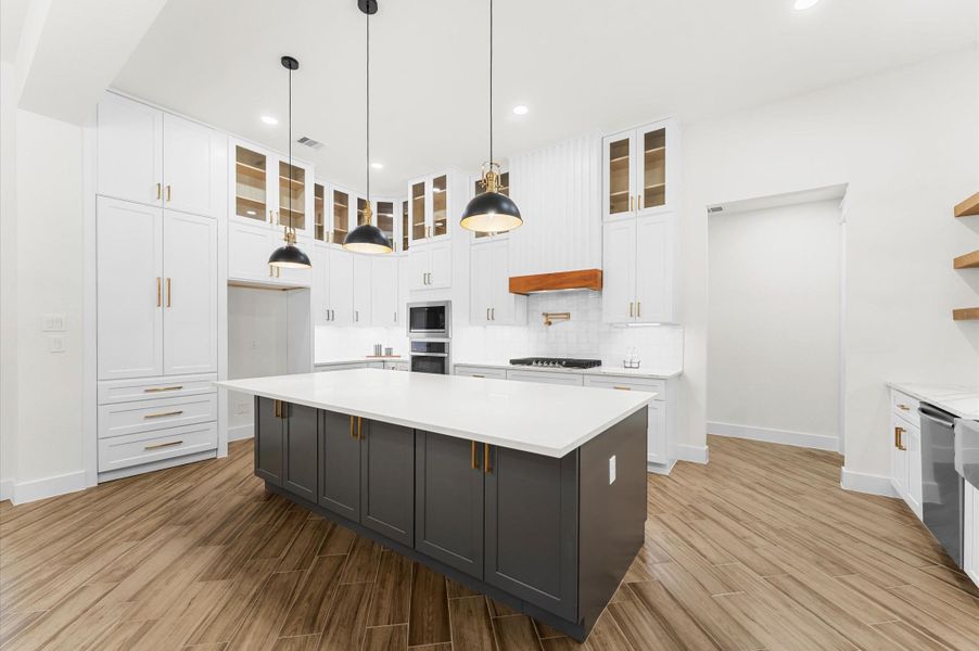 Chef’s dream kitchen featuring custom cabinetry, oversized island, quartz counters, modern fixtures, and abundant windows that overlook the backyard. Chef’s dream kitchen featuring custom cabinetry, oversized island, quartz counters, modern fixtures, and abundant windows that overlook the backyard.