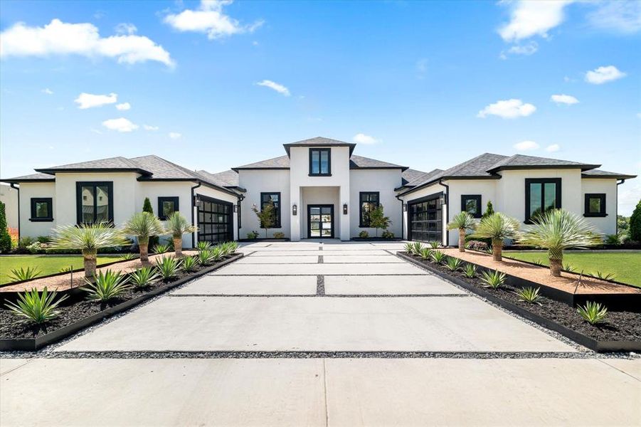 View of front of property featuring a garage, concrete driveway, and stucco siding