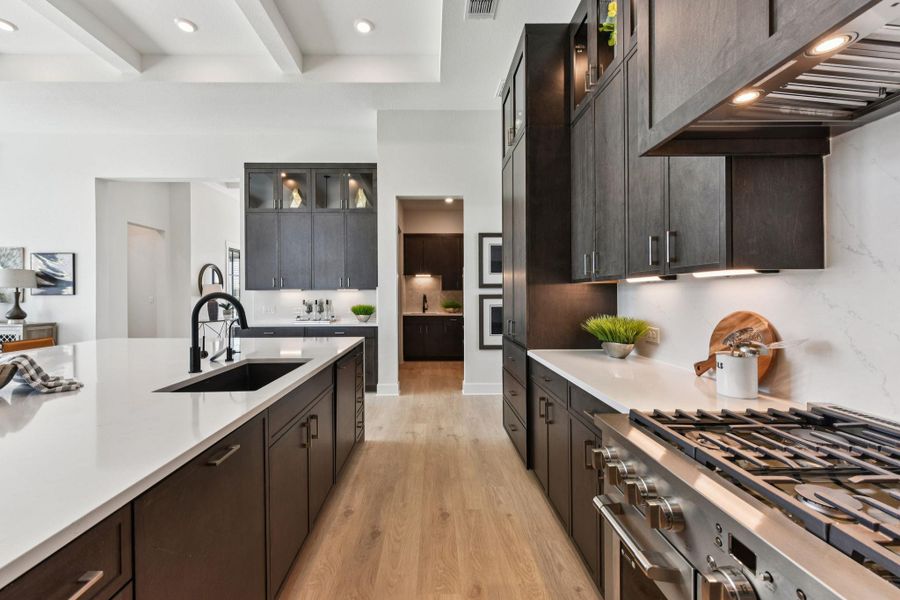 Kitchen with glass fronted cabinets, high end stainless steel range oven, recessed lighting, beamed ceiling, and light wood-type flooring