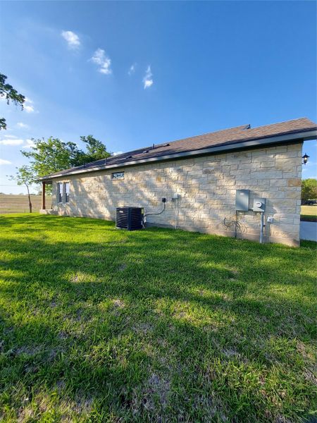 View of side of property featuring a lawn and stone siding