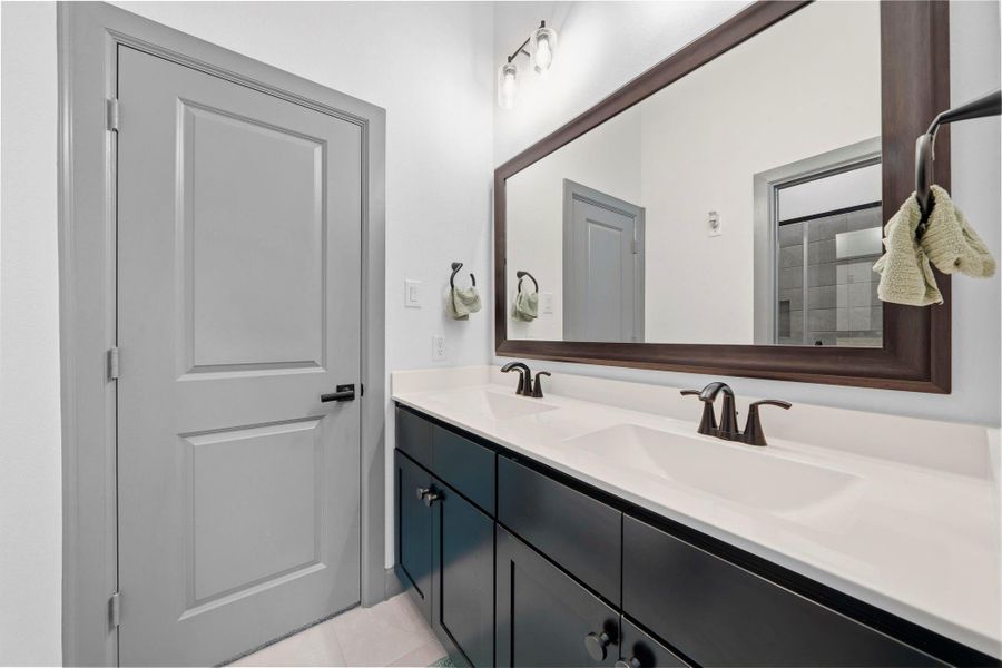 Modern bathroom featuring dual sinks, sleek cabinetry, and a large framed mirror for a clean, contemporary feel.
