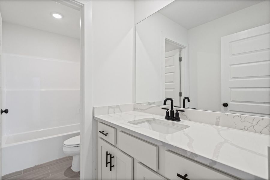 White vanity with a single basin, black faucet, and white countertop