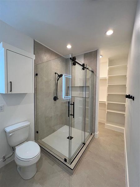 Full bathroom with a shower stall, a spacious closet, and recessed lighting